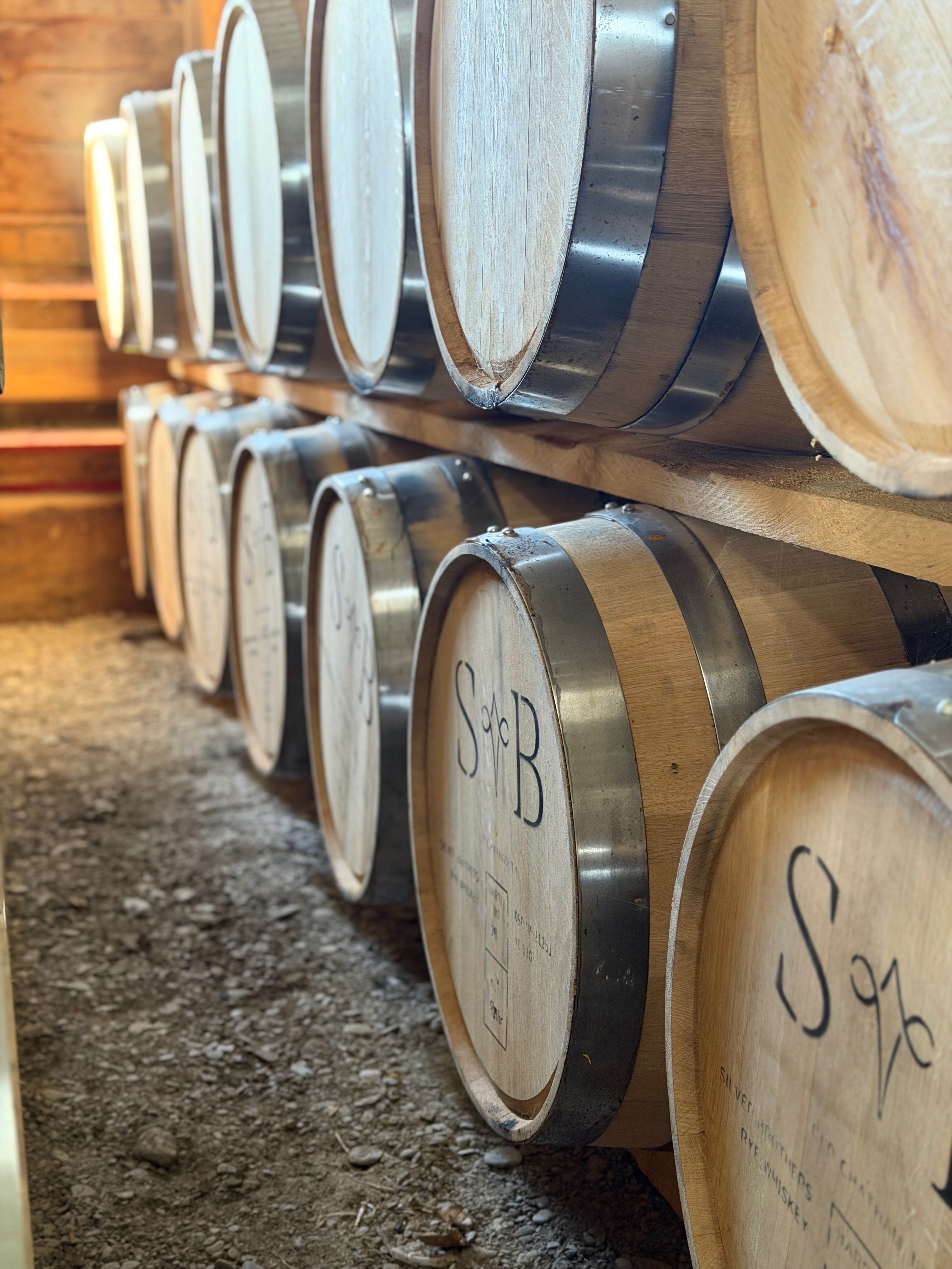Row of wooden barrels with 'S&B' branding in a storage area.