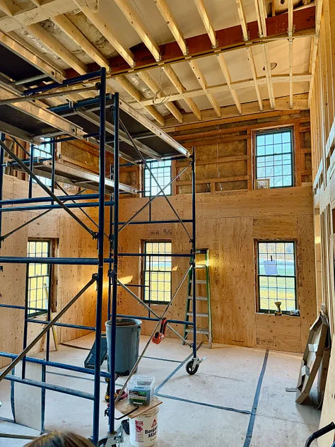 Under construction room with wooden walls and ceiling, scaffolding, and tools.