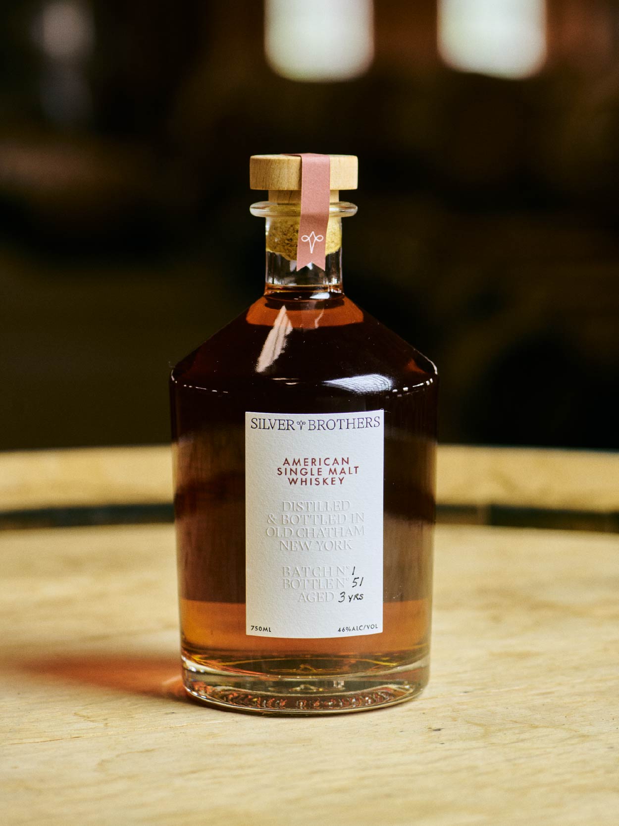 Bottle of Silver Brothers American Single Malt Whiskey on a wooden surface with a blurred background