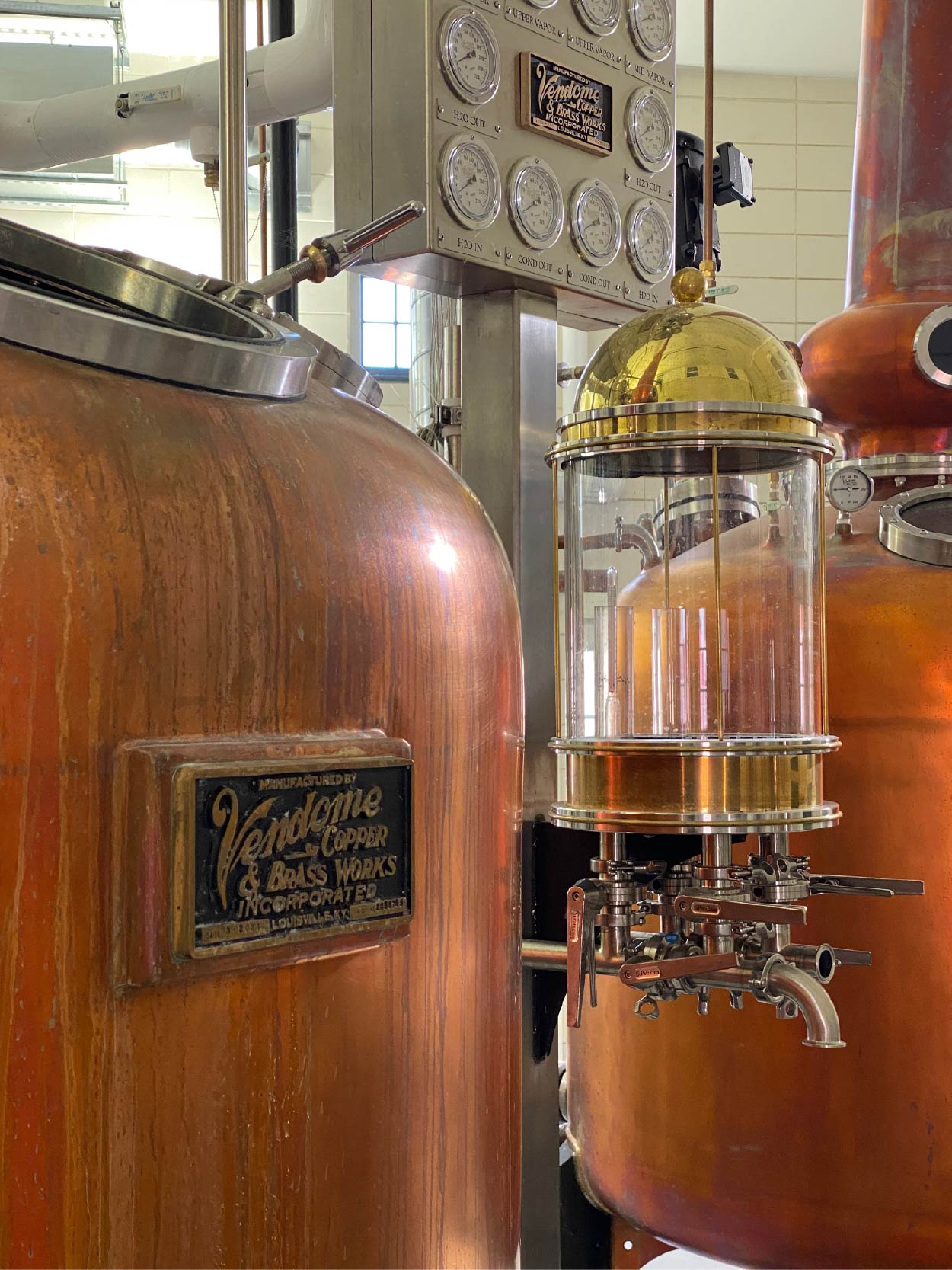 Copper stills with Valdona Copper Works branding in a distillery setting